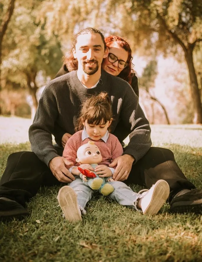 Liseth, Luis y su hija Ayra sentados en el pasto de un parque
